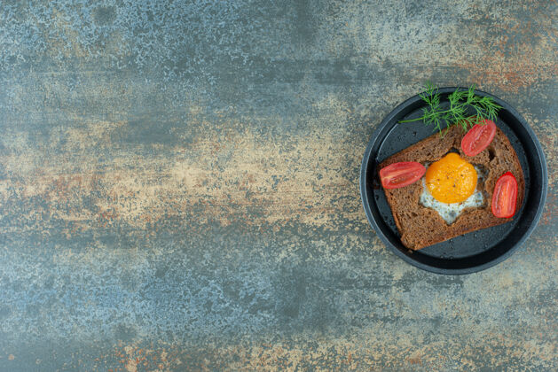 一餐一个深色的平底锅 大理石背景上有煎蛋和西红柿美味好吃鸡蛋