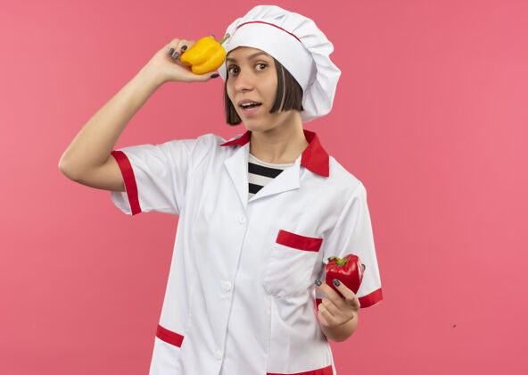 空间令人印象深刻的年轻女厨师在厨师制服举行辣椒孤立的粉红色与复制空间印象粉厨师