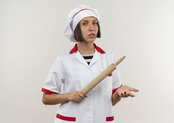 显示自信的年轻女厨师身着厨师制服 手里拿着擀面杖 在白衣上显得孤立无援厨师空别针