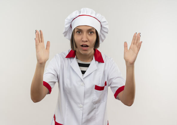提高年轻的女厨师穿着厨师制服 双手举在白色的地板上年轻烹饪女