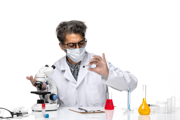 医学正面图身穿白色医疗服的中年科学家正在通过显微镜检查小样本实验室实验室通过