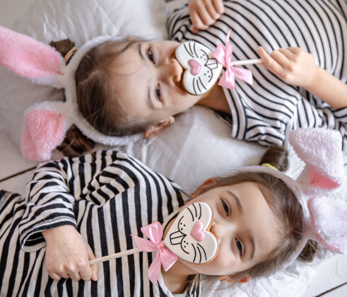童年可爱的小姐妹们 带着复活节姜饼 兔子脸和兔子耳朵节日顶视图小