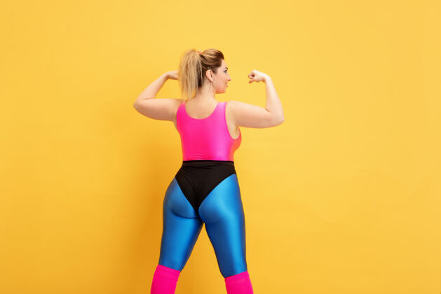 锻炼年轻的白种人大码女模特的黄色训练手臂健身房体重