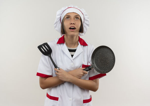 烹饪穿着厨师制服的年轻女厨师手拿抹刀和煎锅 抬头仰望白色的天空向上抹刀锅