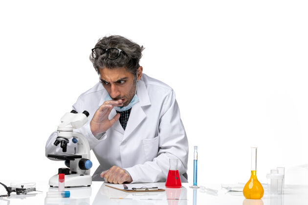 科学穿着白色医疗服的中年科学家使用显微镜的正视图化学人男性