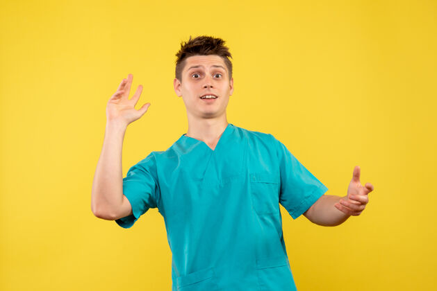 男人正面图黄色背景上穿着医疗服的年轻男医生年轻男性医生背景球