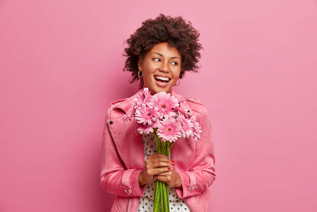 欢呼快乐真诚的美国黑人妇女手持一束非洲菊花 有着积极的节日气氛 自然粉色心情