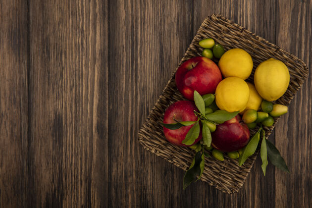 人顶视图的健康水果 如苹果 柠檬和金盏花在柳条托盘上的木制墙壁复制空间苹果健康膳食
