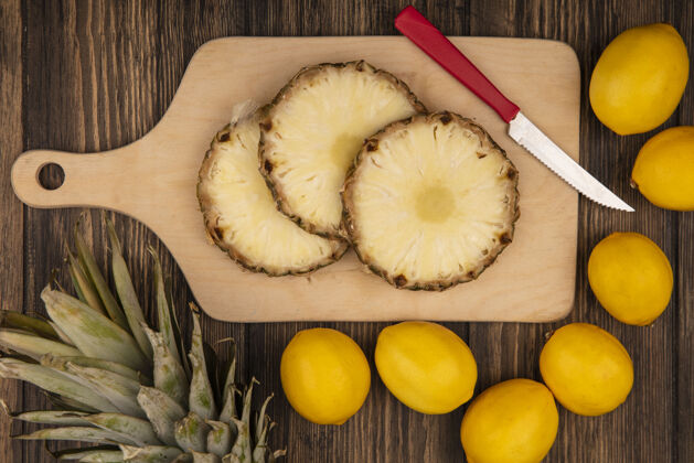 甜点新鲜菠萝的顶视图在木制的厨房板上 刀和柠檬被隔离在木制的墙上景观刀板