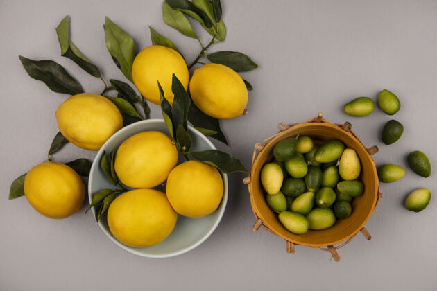 配料新鲜黄色柠檬的顶视图 碗上有叶子 桶上有金盏花 柠檬被隔离在白色的墙上新鲜切片碗
