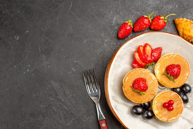 早餐俯瞰美味的薄饼与水果在黑暗的地板上馅饼水果蛋糕甜浆果顶部餐