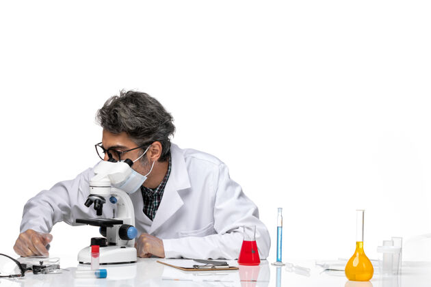 病毒前视图中年科学家穿着特殊的白色西装使用显微镜科学使用实验室外套