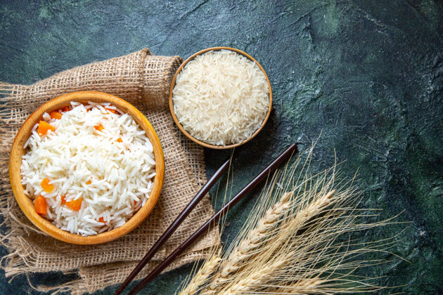 食物俯瞰美味的煮饭和生米在黑暗的桌子上的小盘子里生的午餐盘子