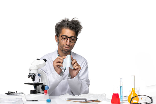 前面正面图身着特殊套装的中年科学家围坐在桌子旁 拿着解决方案化学解决方案科学