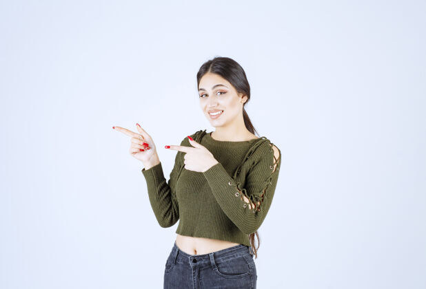 手指一个年轻的女模特站在一边用食指指着照片手指女人肖像