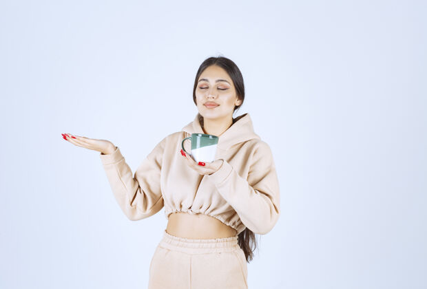 工人一个拿着绿色杯子的年轻女人指着左边的某个地方茶姿势年轻