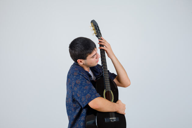 正面十几岁的男孩胸前拿着吉他 穿着t恤 看上去很自信 正对着前方肖像时尚青年