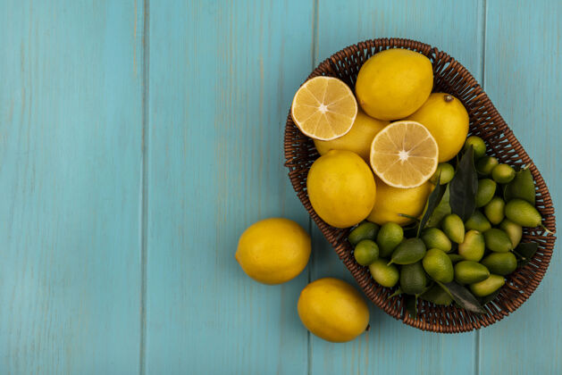 人健康水果的俯视图 如柠檬和金盏花放在桶上 柠檬被隔离在蓝色的木墙上 有复制空间桶素食者柠檬