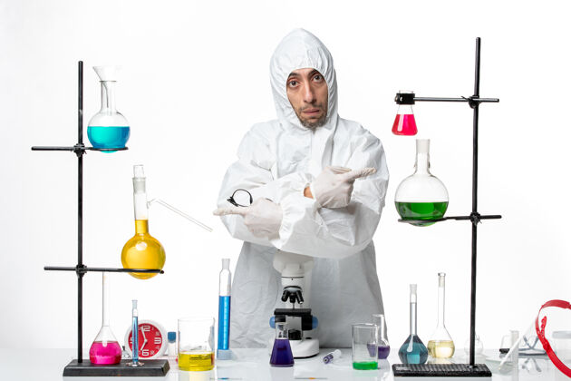 专业正面图穿着特殊防护服的男科学家站在桌子周围 拿着解决方案化学正面科学