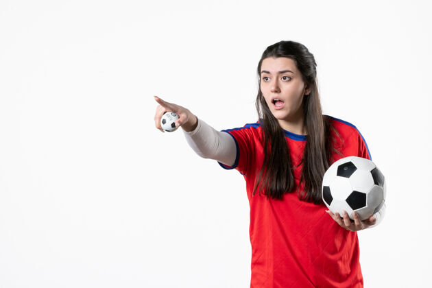 足球前视图穿着运动服的年轻女性 白色墙壁上有足球视图人球员