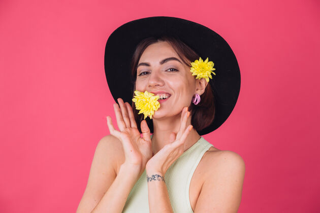 无忧无虑时尚的女人戴着帽子 微笑着两个黄色的紫苑 可爱的捧着一朵花在口中春意盎然 快乐的情感与世隔绝的空间成人植物学肖像