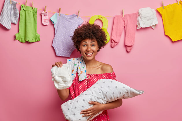 父母快乐的非洲裔美国妈妈关心宝宝 给小女儿换尿布 陪孩子玩 站在家里 摆姿势婴儿卷发女士