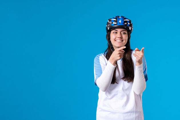 年轻女性前视图穿着运动服的年轻女性 蓝色墙上戴着头盔运动自行车成人