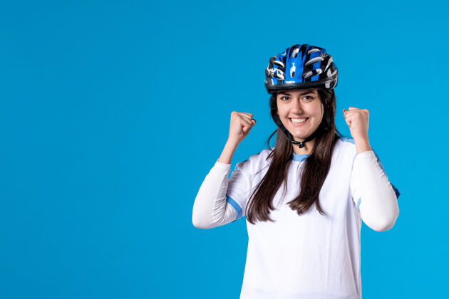 成功前视图穿着运动服的年轻女性 蓝色墙上戴着头盔自行车头盔水平
