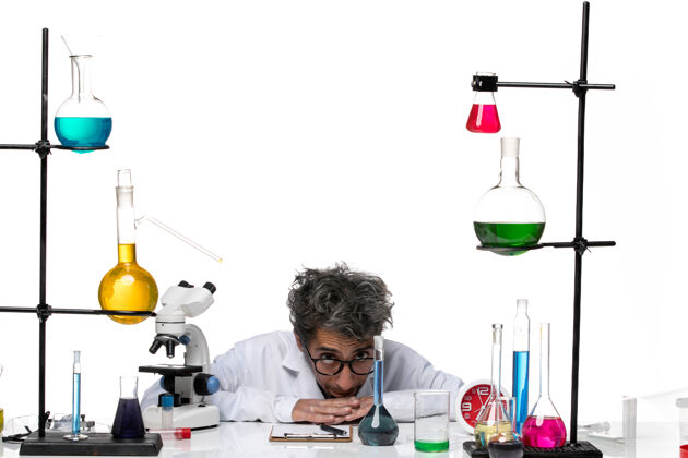 设备前视图穿着白色医疗服的男科学家坐在桌子前 带着解决方案前面科学化学