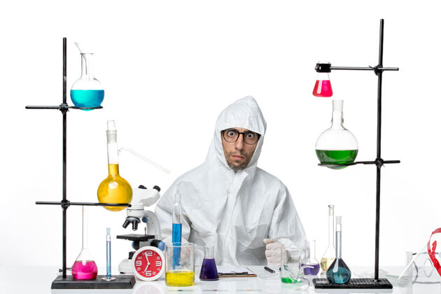 实验室正面图穿着特殊防护服的男科学家围坐在桌子旁 拿着解决方案疾病罐子病毒