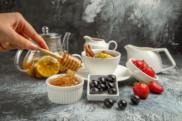 早上前视图甜甜的蜂蜜茶和橄榄在黑暗的地板上早餐盘子杯子前面