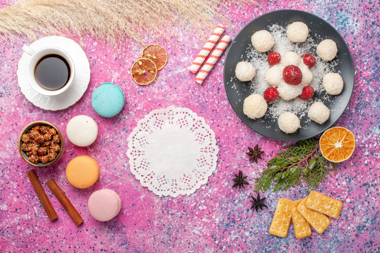 滴滴俯瞰美味的椰子糖与麦卡龙和一杯茶在粉红色的表面茶麦卡龙椰子