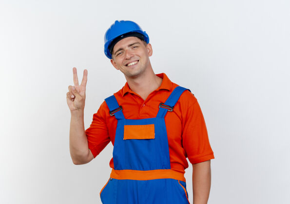 安全微笑的年轻男性建筑工人身穿制服 头戴安全帽 在白色的地板上展示和平的姿态微笑手势男性