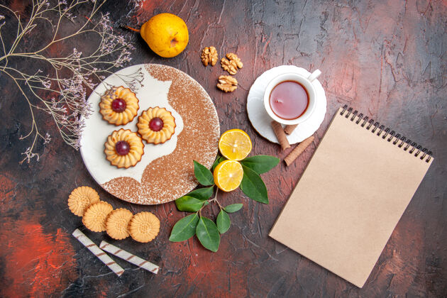 笔记本顶视图小饼干与茶杯在黑暗的桌子糖蛋糕甜饼干杯子美食餐厅