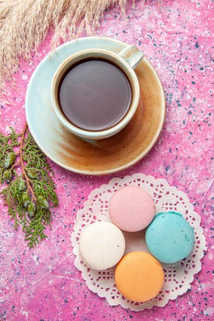咖啡顶视图的法国马卡龙与茶杯在粉红色的表面生的糖果热的