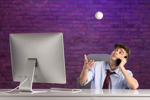 手持前视图：办公桌后面的上班族拿着棒球打电话办公室职员棒球紫色
