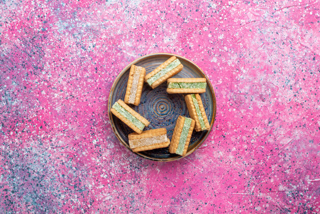 含糖美味的华夫饼干在粉红色表面盘子里的顶视图克制生的闪亮