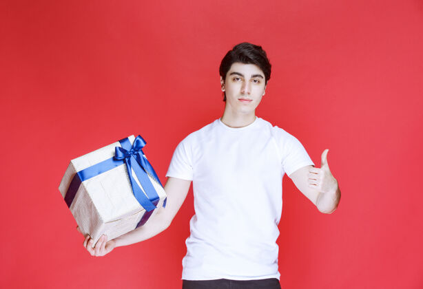 奖励男人拿着一个白色的礼盒 并显示积极的手势满意工人男性