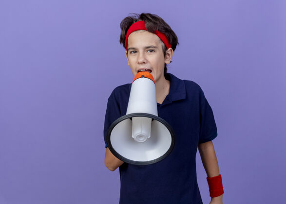 腕带年轻英俊的运动男孩戴着头带和护腕 戴着牙套 看着前面说话的人 被隔离在紫色的墙上衣服牙齿人