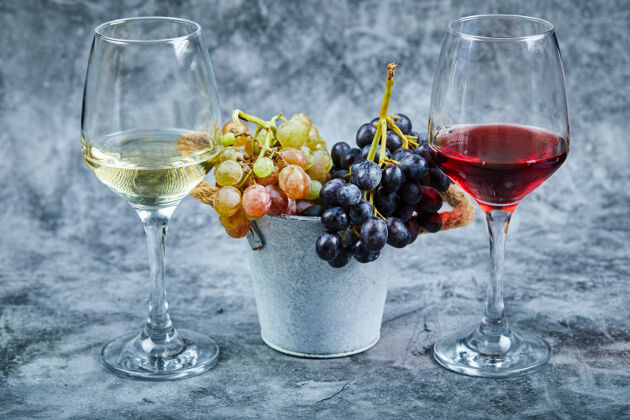 特写大理石背景上的一桶葡萄和一杯葡萄酒酒精深色玻璃