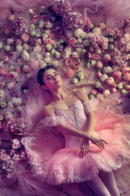 平衡舒适俯瞰美丽的年轻女子在粉色芭蕾舞团tutu周围的鲜花春天的心情和珊瑚光温柔芭蕾运动情绪