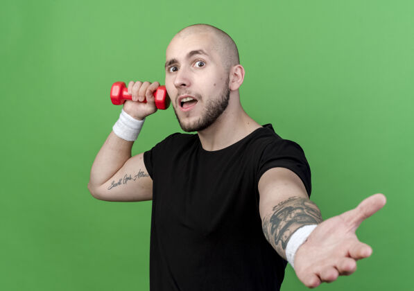 运动年轻人戴着手环 举着哑铃 伸出一只孤立的手站在绿色的墙上男人手势年轻