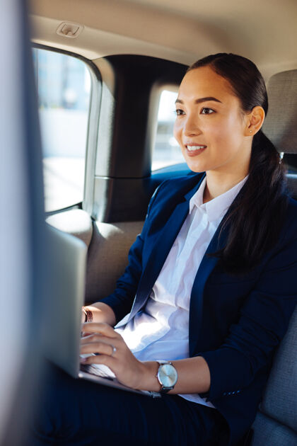 笔记本电脑总是很忙愉快自信的女商人在车里用笔记本电脑工作基础设施创新出租车