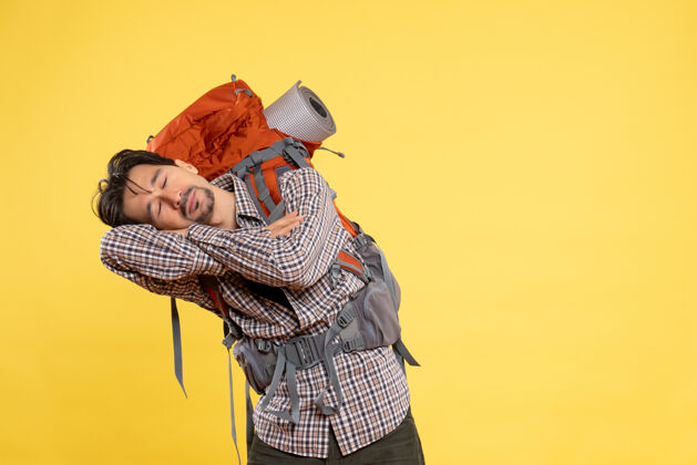 山正面图：年轻男子背着背包徒步旅行 睡在黄色的床上人背包成人
