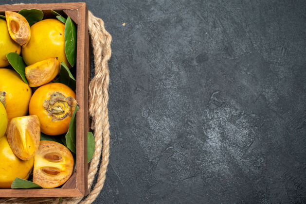 顶部顶视图新鲜甜甜的柿子在盒子里放在深色的桌子上 成熟的水果背景食物盒子