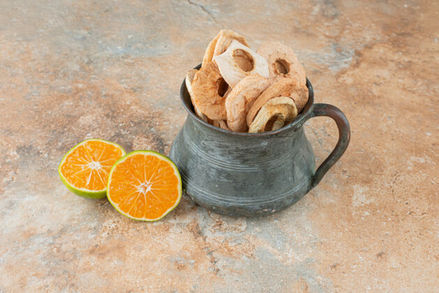 干的古老的茶壶装满了苹果干和半切的橘子古董新鲜水果