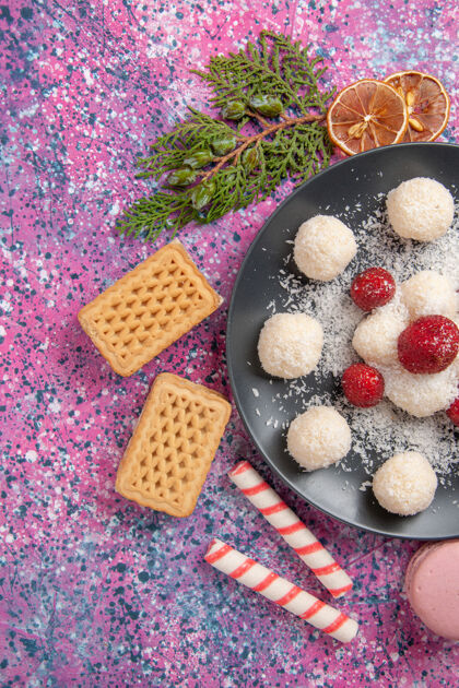 草莓美味的椰子糖甜球与华夫饼和麦卡龙在粉红色表面俯瞰顶视图甜点食物