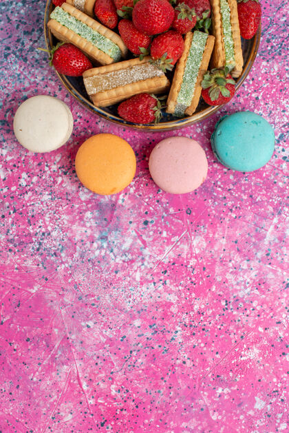 麦卡龙美味的华夫饼干俯视图 粉色表面有马卡龙和新鲜的红色草莓新鲜五颜六色糖
