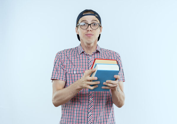帽子高兴的年轻学生男孩戴着书包 戴着眼镜和帽子 手里拿着白色的书背景白色包
