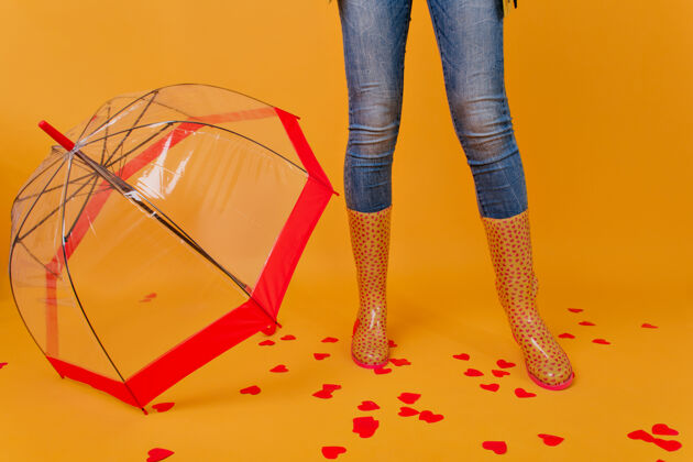 阳伞身材匀称的女士穿着牛仔裤站在红色时髦的阳伞旁雨伞旁穿着胶鞋的女性腿部室内照片天气女人腿
